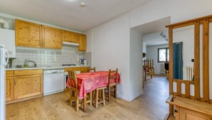 Una cucina con mobili in legno, un tavolo da pranzo con sedie e vista su un'altra stanza.
