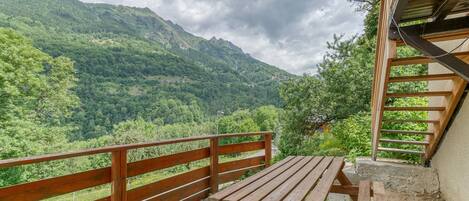 A wooden deck with a picnic table overlooking a mountainous landscape.