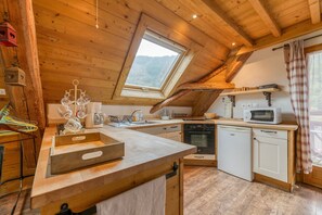A kitchen with wooden beams, a skylight, a microwave, and a dishwasher.