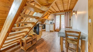 En interiör med träinredning, bestående av ett kök, en matplats och ett loft.