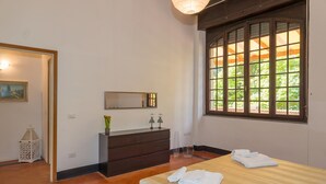 Ein Hotelzimmer mit Bett, Schminktisch, Spiegel, Fenster mit Aussicht und einer Tür zu einem weiteren Raum.