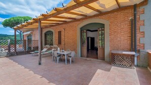 Eine überdachte Terrasse mit einer Ziegelwand, einem Tisch mit Stühlen und einer Holzpergola.