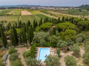An aerial view of a property with a swimming pool surrounded by trees and landscaped gardens.