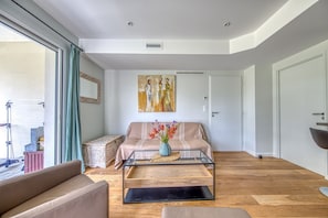 Un salon avec un canapé, une table basse en verre et un tableau accroché au mur.