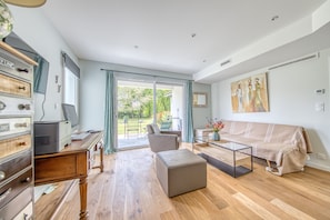 Un salon moderne avec un canapé, un pouf et une table basse en verre.