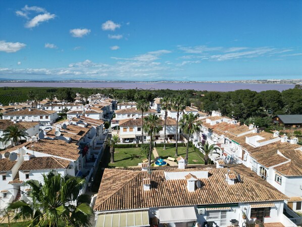 A residential area with white buildings, tiled roofs, and palm trees.