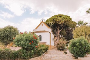 A white building with a tiled roof, surrounded by various plants and trees. - Apartment 'Bungalow 58' with Shared Pool, Wi-Fi and Air Conditioning (Torrevieja)