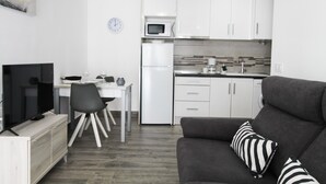 A modern kitchen with white cabinets, a microwave, and a clock on the wall.