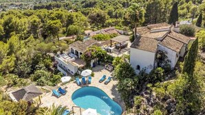 A villa with a swimming pool, outdoor seating, and a view of the surrounding landscape. - Villa 'Caroix' with Sea View, Wi-Fi and Air Conditioning (Xàbia)