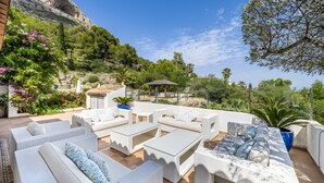 An outdoor patio with wicker furniture, a gazebo, and a view of a mountainous landscape. - Villa 'Caroix' with Sea View, Wi-Fi and Air Conditioning (Xàbia)