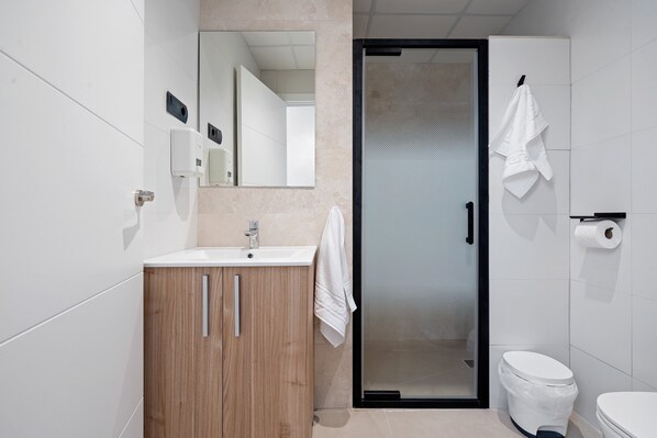 A modern bathroom with a wooden vanity, a glass shower enclosure, and a white toilet.