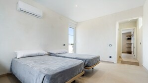 A bedroom with two beds, a ceiling air conditioner, and a view of the outdoors.