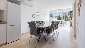 A modern kitchen with a built-in refrigerator, a dining table with chairs, and a view through a glass door to an outdoor patio.