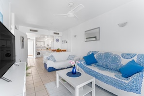 A modern living room with a white sofa, a coffee table, and a TV. - Apartment 'In Playa Flamenca' with Shared Pool, Wi-Fi and Air Conditioning (Playa Flamenca)