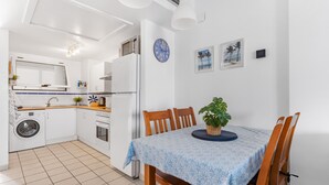 Une cuisine compacte équipée d’un lave-linge, d’une table à manger avec des chaises et d’une horloge murale.