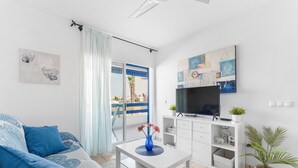 Un salon moderne avec un canapé, une table basse, un téléviseur et un balcon offrant une vue agréable.