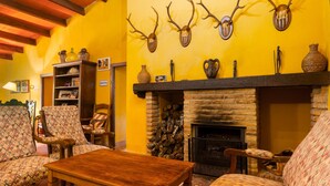 A cozy living room with patterned furniture, a fireplace, antler wall decor, and a bookshelf.