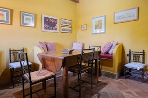 A dining area with a wooden table and chairs, a woven basket, and a bench with a red cushion. - Apartment 'Chirrin' with Mountain View, Private Terrace and Private Garden (Constantina)