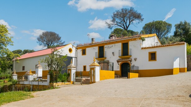 A traditional building with a red roof, white walls, and yellow trim.