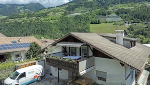 Une maison avec un balcon, des panneaux solaires et un fourgon garé devant.