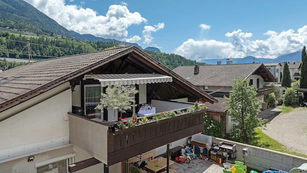 Un bâtiment de style chalet doté d’un balcon, d’un coin repas et offrant une vue sur les montagnes environnantes.