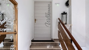 Un escalier menant à une porte sur laquelle est affiché un panneau indiquant « Willkommen » (Bienvenue).