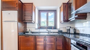 Eine Küche mit Holzausstattung, einem Einbauofen, einem Kühlschrank und einem Fenster mit Blick.