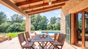 Eine Terrasse im Freien mit Tisch und Stühlen, einem Pool und einer Steinmauer.