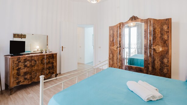 A room with a bed, a wooden wardrobe, a television on a cabinet, and a mirror. - Holiday Home 'La Vanedda' with Private Terrace, Wi-Fi and Air Conditioning (Partanna)