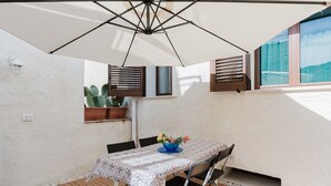 A patio with a table, chairs, a blue bowl with flowers, and a white umbrella. - Holiday Home 'La Vanedda' with Private Terrace, Wi-Fi and Air Conditioning (Partanna)