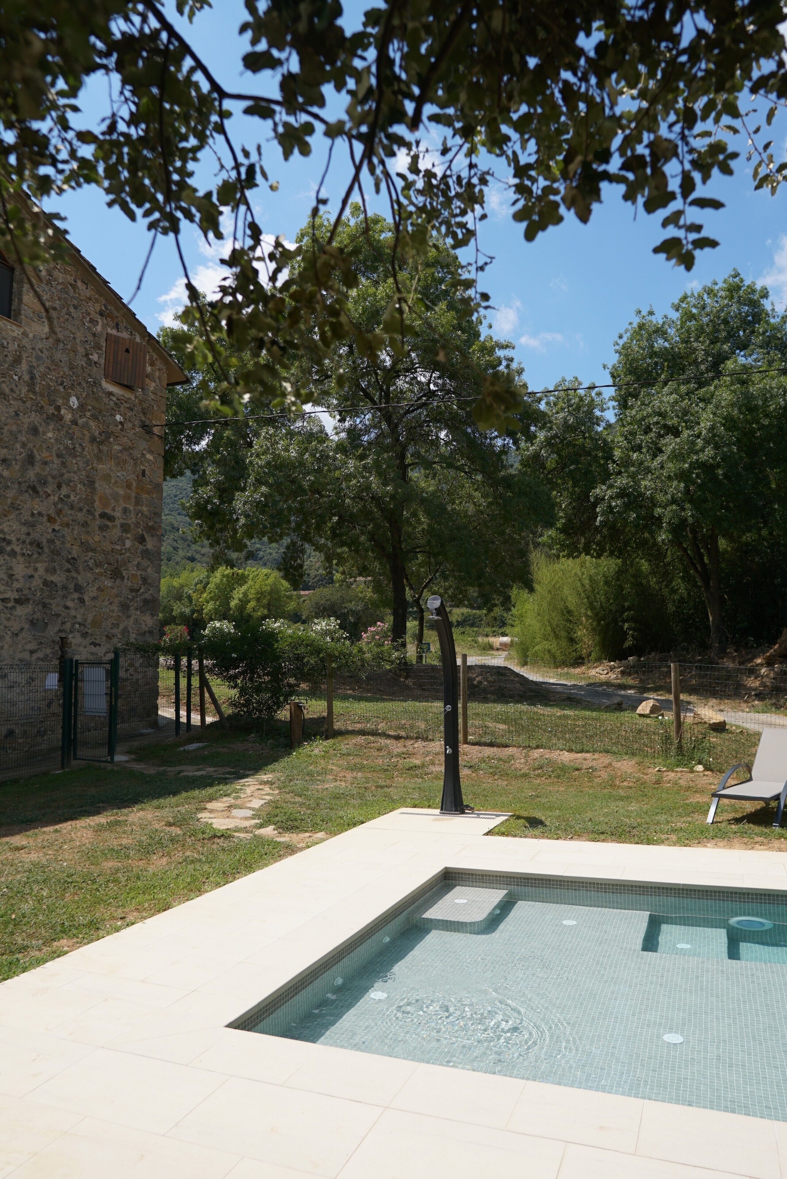 Una piscina con un edificio de piedra y árboles al fondo.