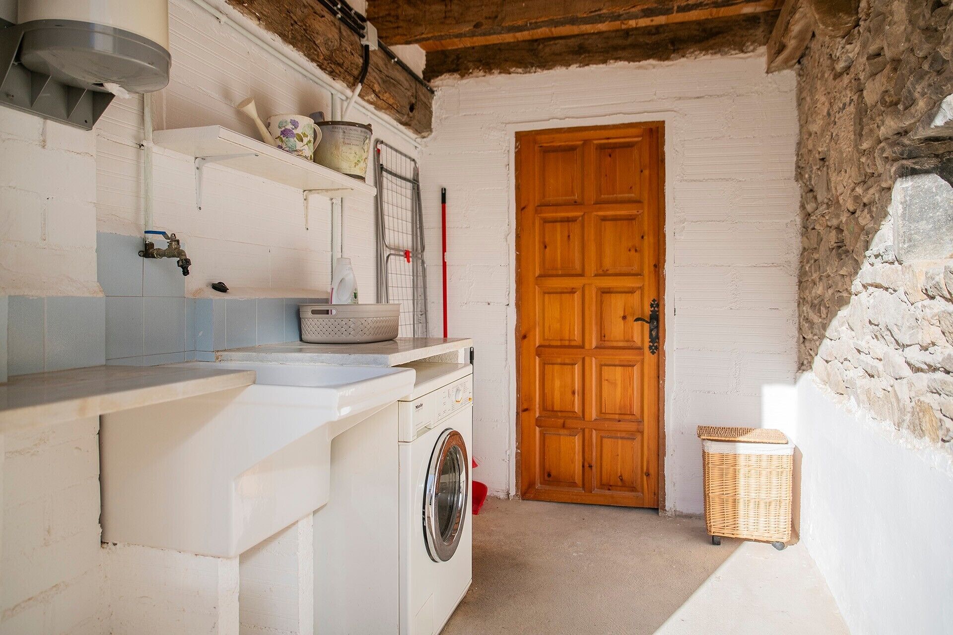 A compact laundry area with a washing machine, a drying rack, and a wooden door.