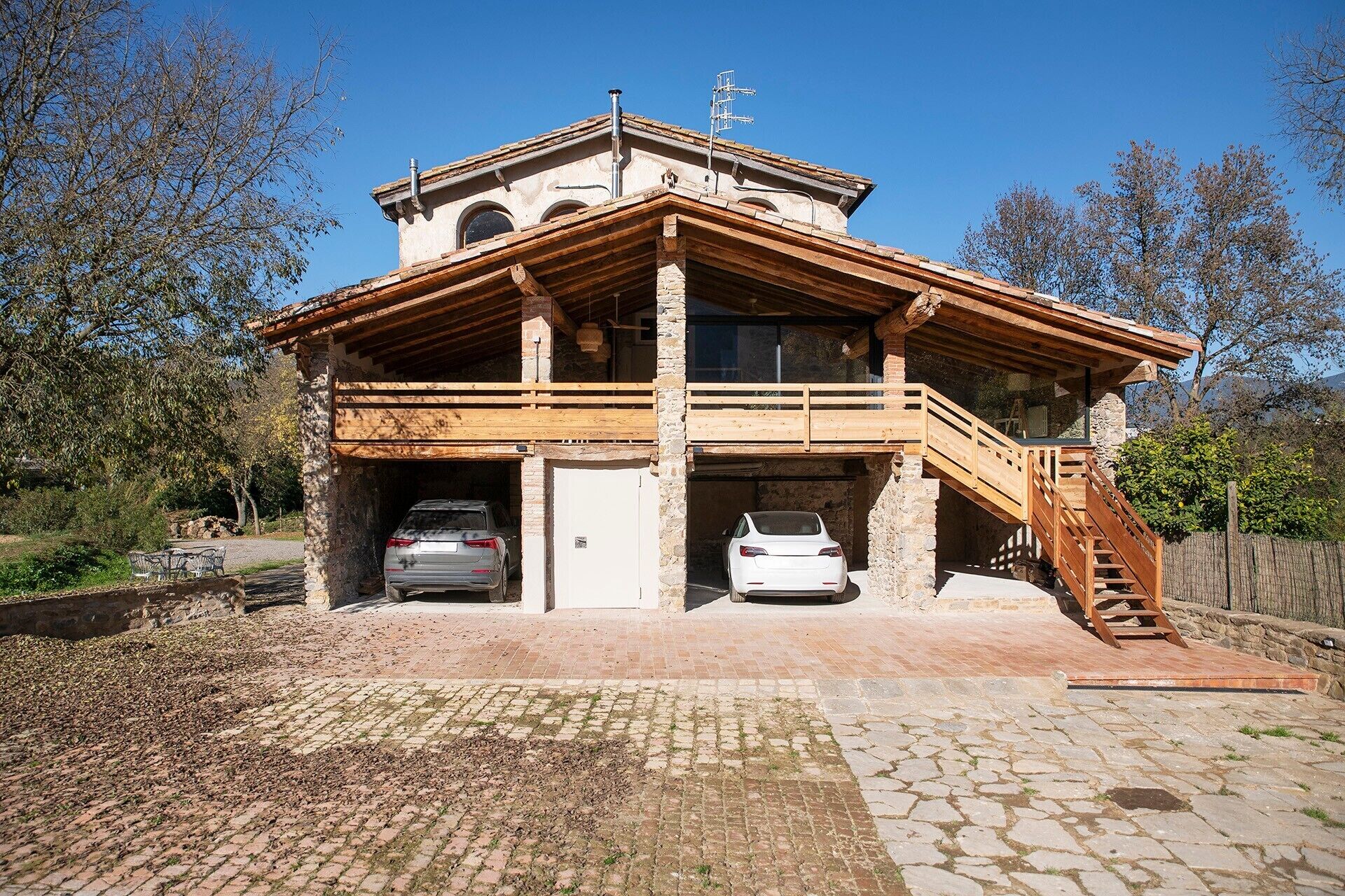 A two-story stone building with a wooden balcony and a staircase leading to the upper level.