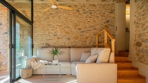 Un salon chaleureux avec un mur en pierre, un canapé, une table basse et un escalier.