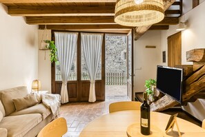 A cozy living room with a sofa, a dining table with a bottle, and a TV.