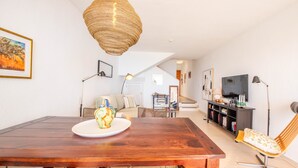 A dining area with a wooden table, wicker chairs, and a hanging light fixture. - Apartment 'Casa Emma' with Sea Views, Wi-Fi and Air Conditioning (Almuñécar)