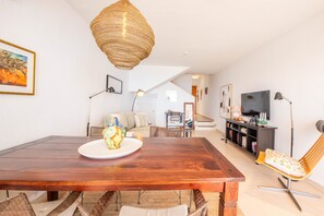 Un comedor con una mesa de madera, sillas de mimbre y una lámpara colgante.