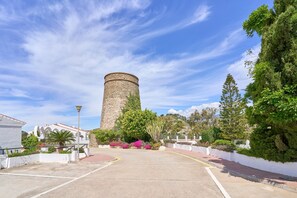 A courtyard with a stone tower, white walls, and lush greenery.