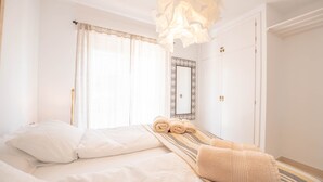 A hotel room with a bed, a mirror, and a window with curtains. - Apartment 'Casa Emma' with Sea Views, Wi-Fi and Air Conditioning (Almuñécar)