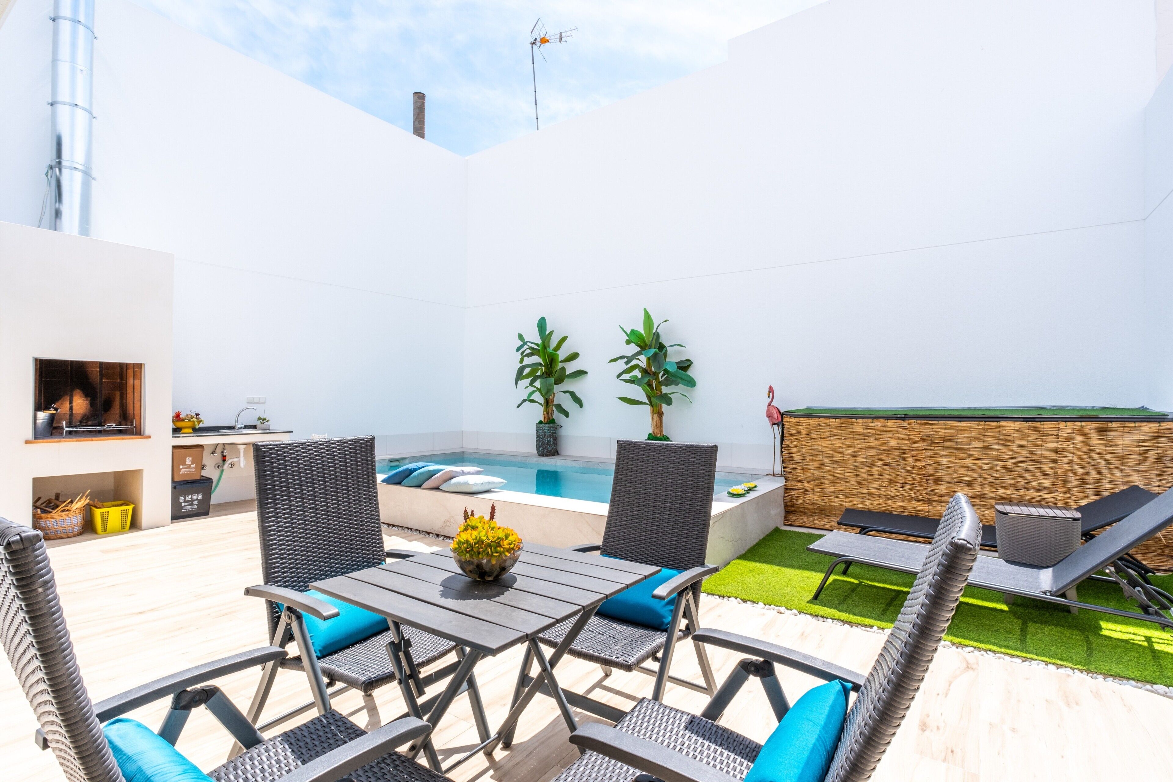 Une terrasse extérieure moderne, dotée d’une piscine, de coins salon et de plantes en pot.