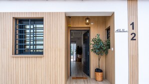 Ingresso di un edificio moderno con facciata in legno, un cancello in metallo, una pianta in vaso e una targa con l'indicazione dell'indirizzo Alttalban 12.