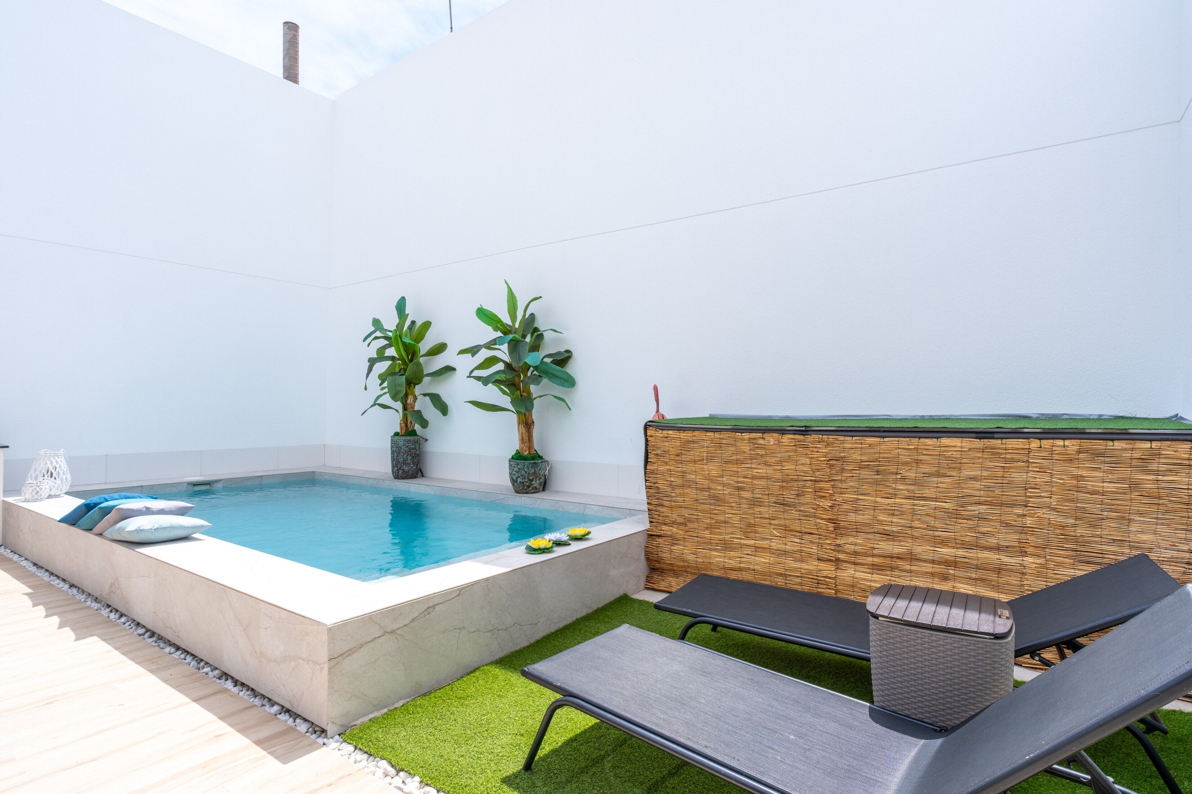 Una piscina con sillas de descanso y plantas en macetas.