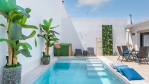 Una piscina con lettini e piante in vaso.