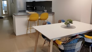 Eine moderne Küche mit weißen Schränken, einem eingebauten Backofen und einem schwarzen Kühlschrank.