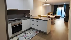 Eine moderne Küche mit weißen Schränken, einem eingebauten Ofen und einem Essbereich mit Tisch und Stühlen.