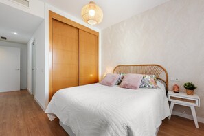 Ein Schlafzimmer mit einem Bett, einem Holzschrank, einem Nachttisch mit Lampe sowie einer Wandleuchte.