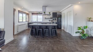Une cuisine moderne dotée d’un îlot central, de tabourets de bar, d’un four encastré et d’une grande fenêtre.