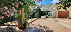 Un patio con plantas en macetas, una fuente y un edificio con garaje.