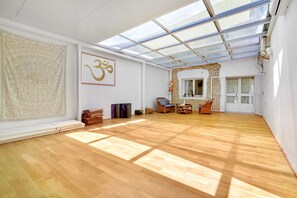 Una habitación amplia con suelo de madera, un ventanal con vistas, una obra de arte colgada en la pared y una silla.