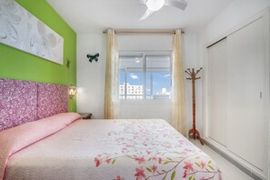 A bedroom with a bed, a window with curtains, a coat rack, and a ceiling fan. - Apartment 'Vistas Al Mar A' with Sea View, Wi-Fi and Air Conditioning (Calp)